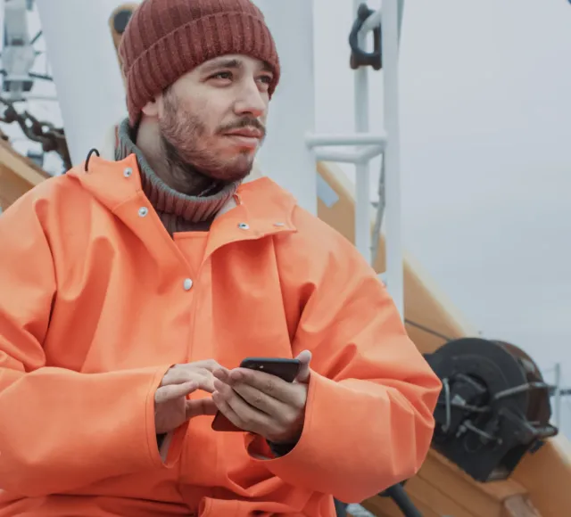 Pescador usando el móvil a bordo de un barco pesquero